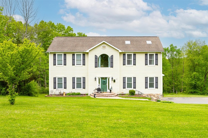 Colonial house with a front lawn and a shingled roof