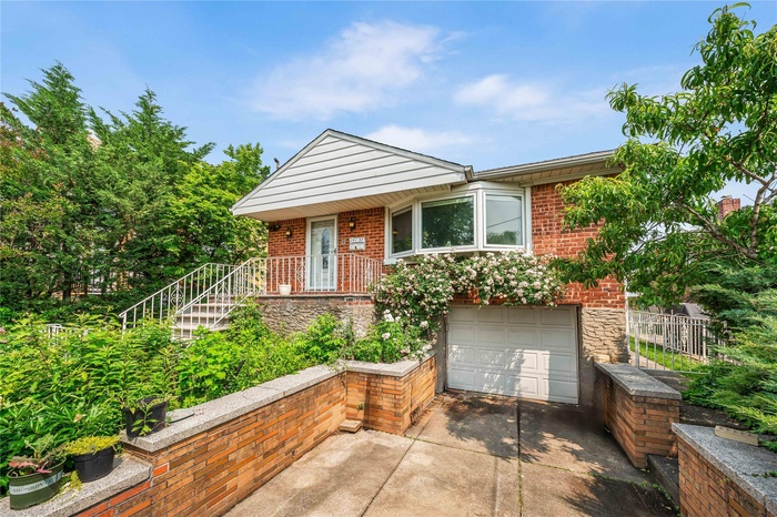 View of front of house featuring a garage, concrete driveway, brick siding, and stone siding