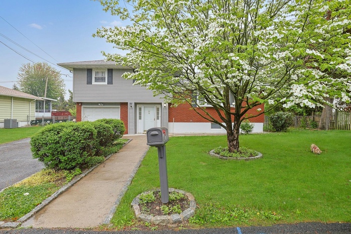 View of front of house with a front yard, brick siding, an attached garage, and fence