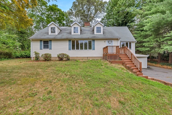 Cape cod home featuring a front lawn, a chimney, and roof with shingles