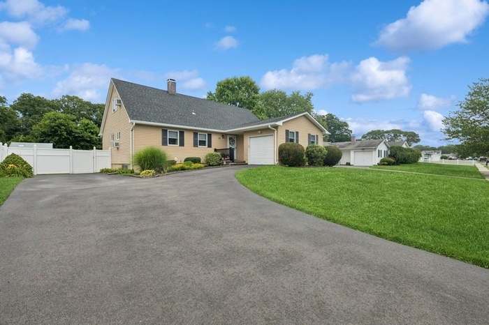 Ranch-style house with a garage, driveway, a chimney, and a shingled roof