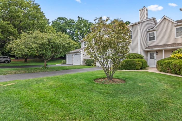 view of property featuring driveway, a front lawn, and a chimney