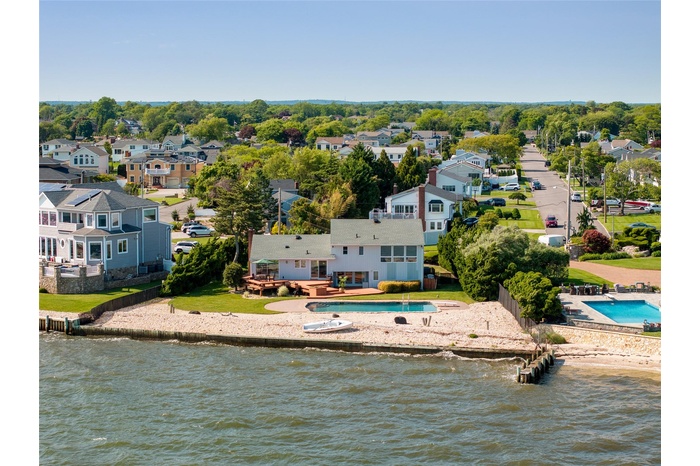 Aerial perspective of suburban area with a pool and a large body of water