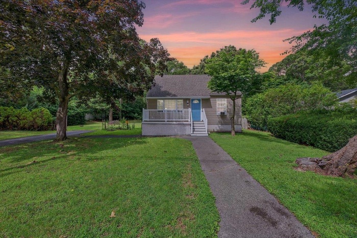 Bungalow-style house with covered porch, a lawn, and roof with shingles