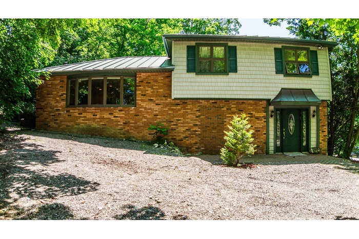 Split level home with a standing seam roof, brick siding, and metal roof