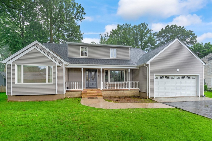Traditional-style house with concrete driveway, a shingled roof, a garage, and a front lawn