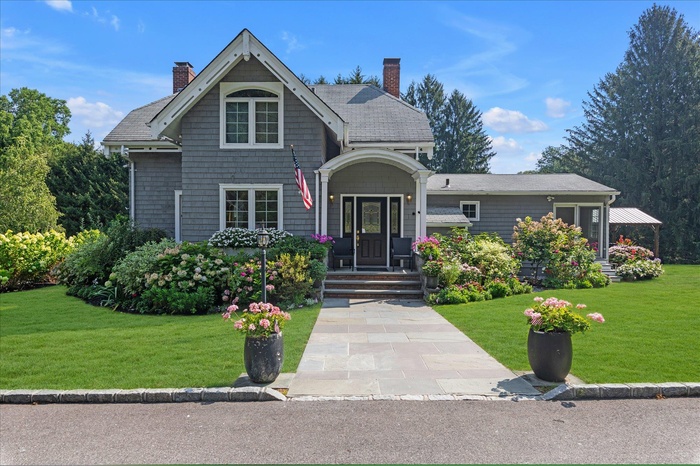 Shingle-style home with a chimney and a front lawn
