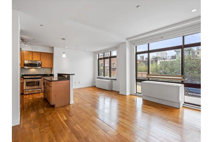 Living Room and Kitchen with appliances with stainless steel finishes, open floor plan, brown cabinets, wood finished floors, and tasteful backsplash