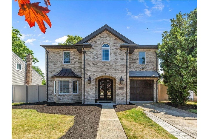 View of front facade featuring brick siding, french doors, driveway, and an attached garage
