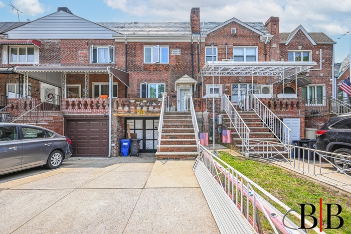 View of property with concrete driveway, brick siding, a garage, a high end roof, and stairs