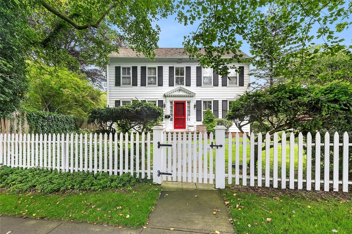 Colonial house with a gate and a fenced front yard
