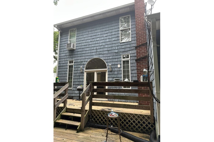 Rear view of house featuring a wooden deck and a chimney