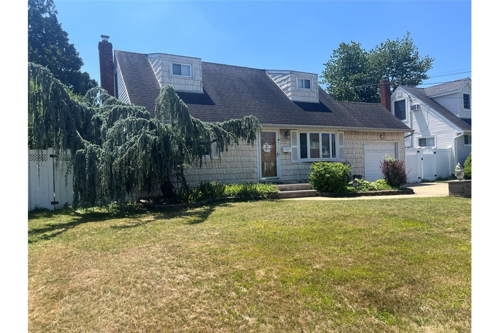 View of front facade featuring a garage and a chimney