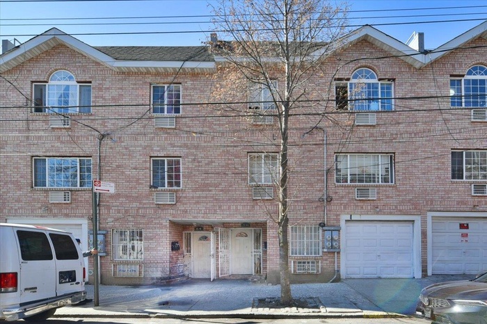 View of front of home featuring a shingled roof, brick siding, an attached garage, and a wall mounted AC