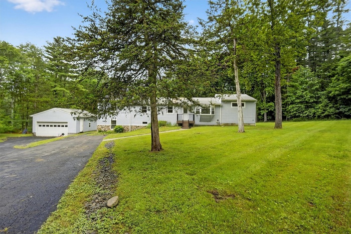 View of front facade featuring driveway, a front yard, and a garage