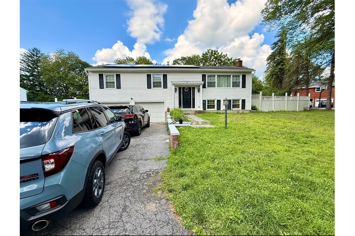 Bi-level home featuring a garage, asphalt driveway, and a chimney