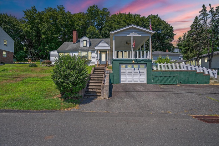 View of front of house with a ceiling fan, a garage, stairs, driveway, and a chimney