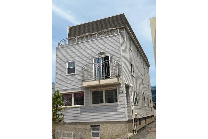 Back of house with a balcony and roof with shingles