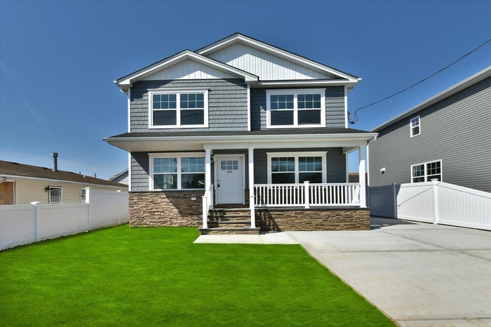 Craftsman-style house featuring fence, covered porch, a front yard, and stone siding