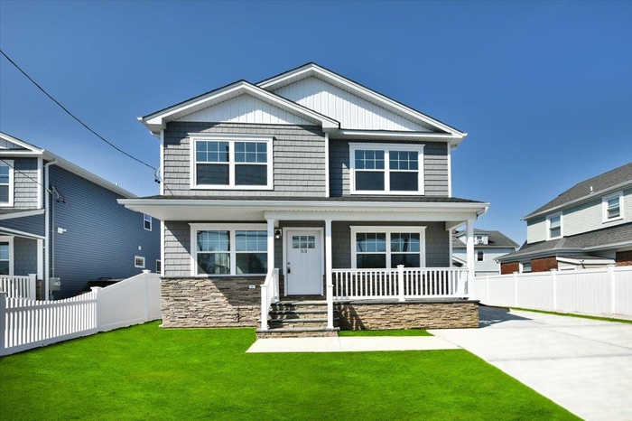 Craftsman-style home featuring a porch, a front yard, concrete driveway, and fence