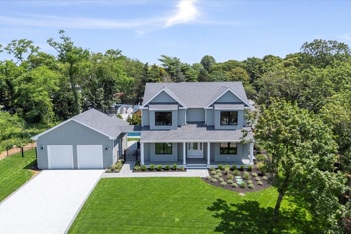 View of front facade featuring a garage, covered porch, roof with shingles, a front yard, and concrete driveway