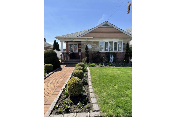 View of front of house featuring covered porch, brick siding, and a front yard