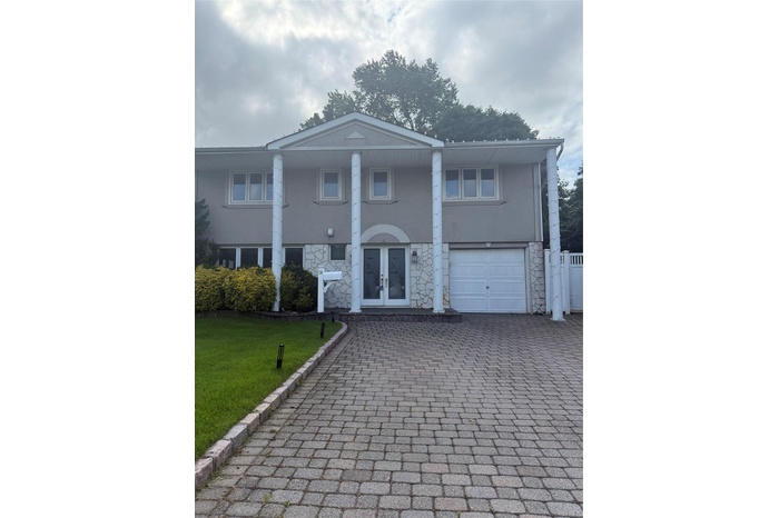 Neoclassical home featuring a garage, stucco siding, french doors, stone siding, and decorative driveway