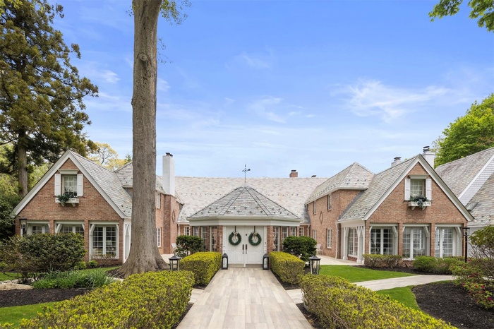 View of front of house with a high end roof, brick siding, and a chimney