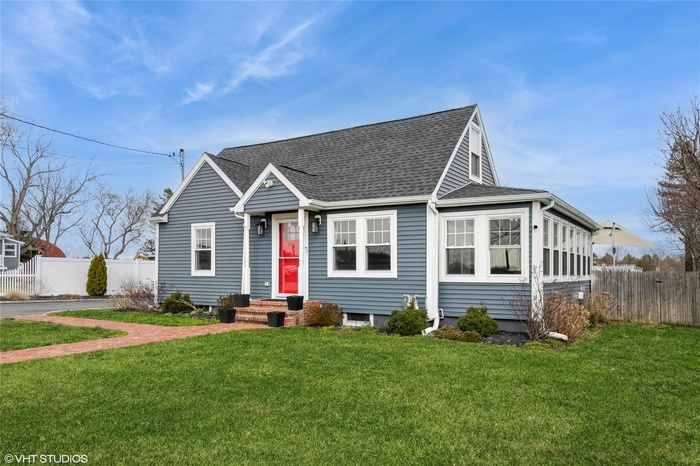 Farmhouse-style house with roof with shingles, fence, and a front lawn