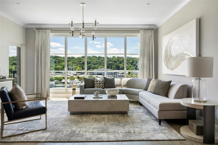 Living room with crown molding, wood-type flooring, and a notable chandelier