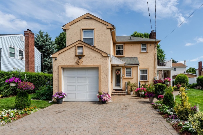Traditional-style home with decorative driveway, a garage, stucco siding, and a chimney