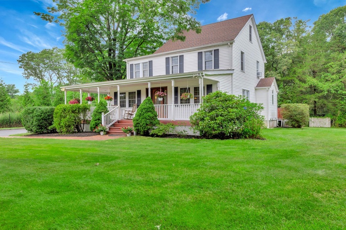View of front of home featuring covered porch, a front yard, and a shingled roof