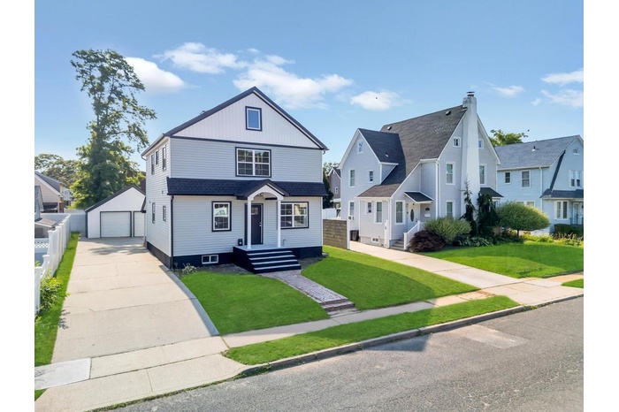 View of front of property featuring a detached garage, an outdoor structure, driveway, and a residential view