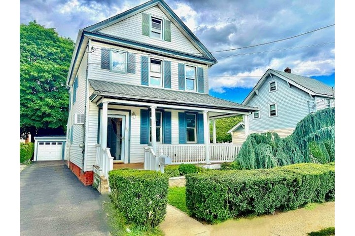 View of front of property featuring covered porch, an outdoor structure, and asphalt driveway
