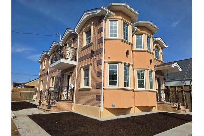 View of property exterior with brick siding, stucco siding, a balcony, and fence