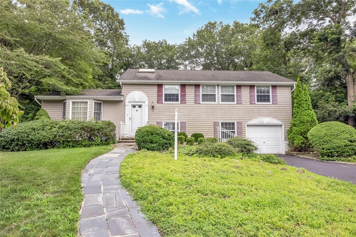 Split level home featuring a front yard, a garage, and asphalt driveway