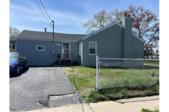 View of front of house featuring entry steps, fence, a chimney, and a front yard