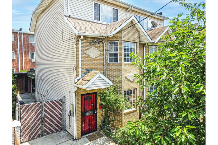 Townhome / multi-family property featuring brick siding, a gate, and a shingled roof
