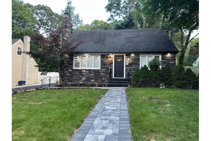 View of front of home with entry steps, stone siding, and a shingled roof