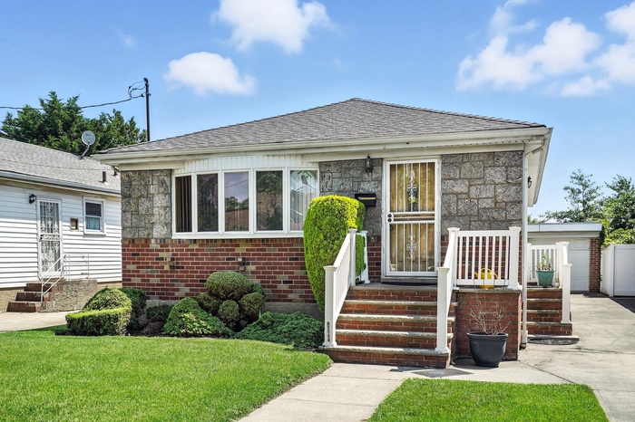 Featuring a front yard, brick siding, stone siding, and a shingled roof