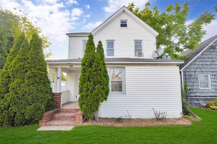 Back of property with a yard and a porch