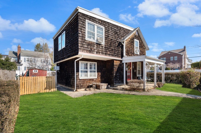 Back of property with fence and a lawn