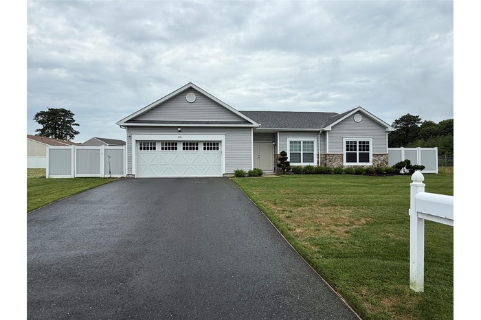 Ranch-style home with driveway, a garage, and stone siding