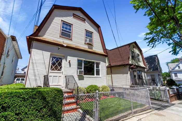 Dutch colonial with a gambrel roof, a fenced front yard, a gate, stucco siding, and cooling unit