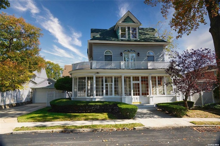 Victorian home with fence, a garage, a balcony, and a sunroom