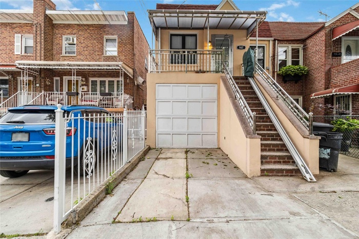 View of property featuring concrete driveway, stucco siding, a garage, brick siding, and stairs