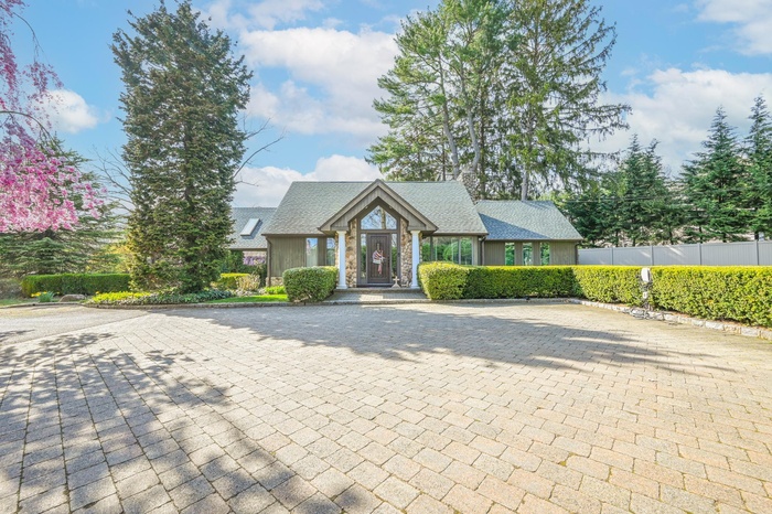 View of front of house with fence and roof with shingles