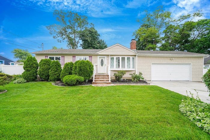 Ranch-style home featuring a chimney, an attached garage, driveway, and a front yard