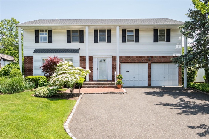 View of front of home with driveway, brick siding, a garage, and a front yard