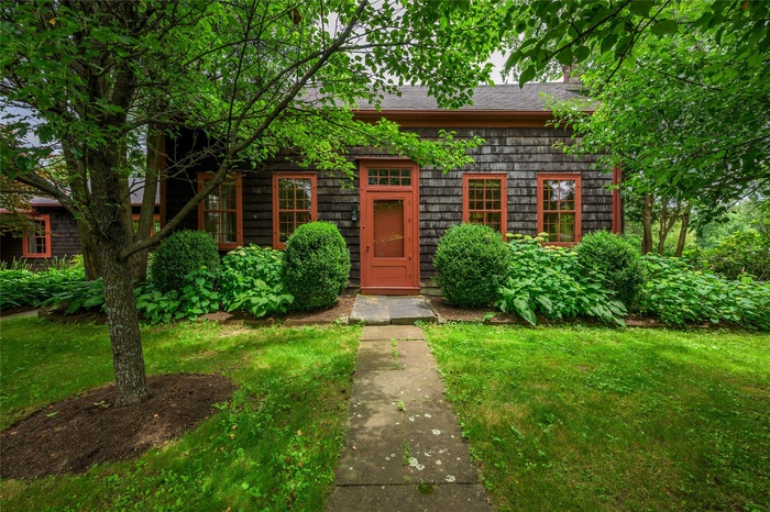 View of front of property featuring a shingled roof and a front yard
